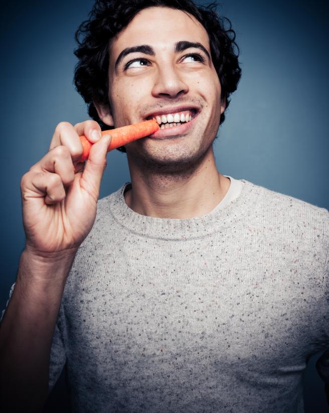 Young man eating a carrot