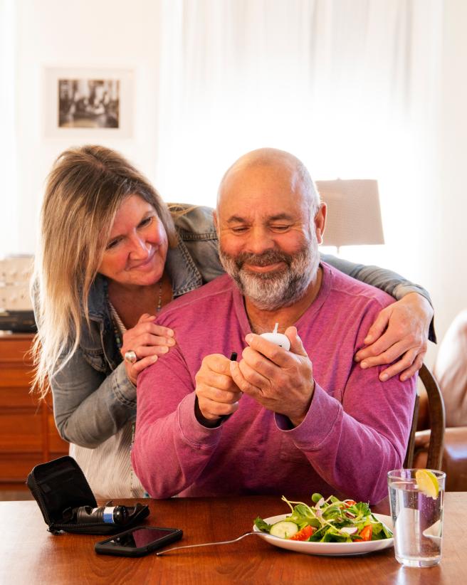 A diabetic patient checking his blood sugar at home with the support of his wife. 