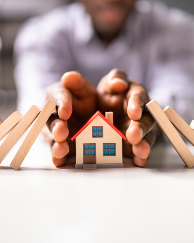 Hands protecting a home.