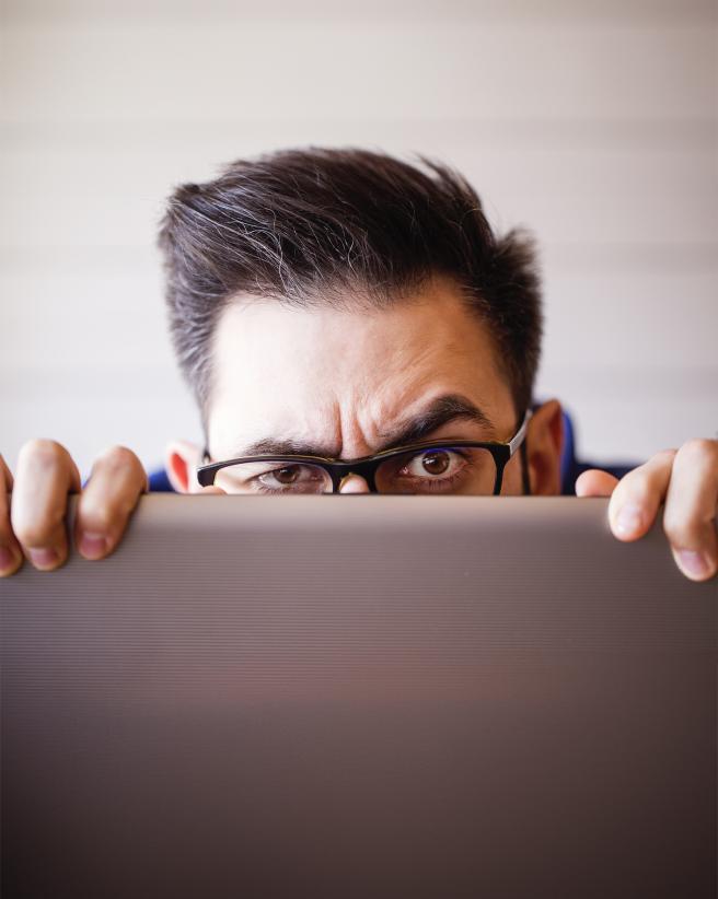 man peaking over his computer