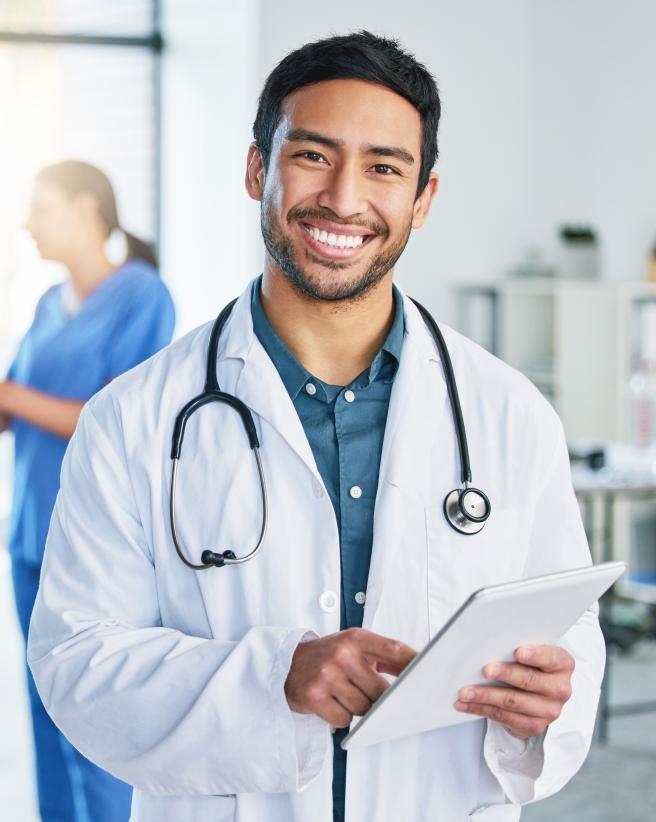 smiling doctor with stethoscope and clipboard in hospital setting