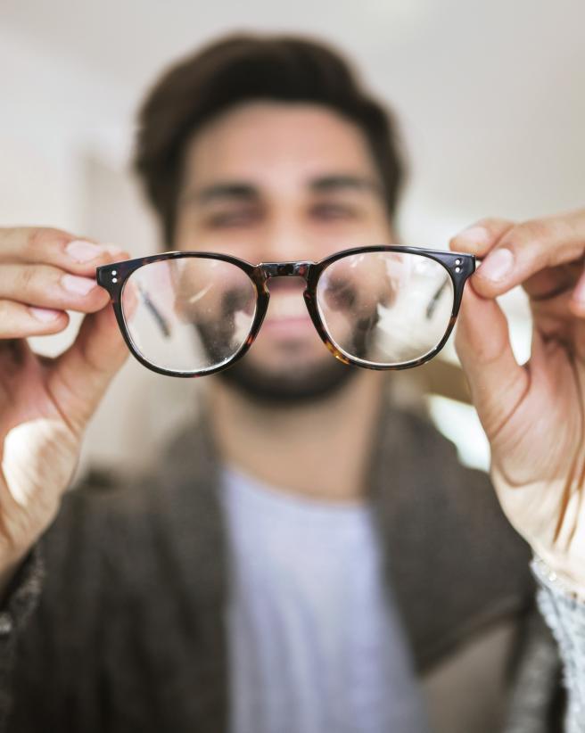 Man holding glasses away from his face