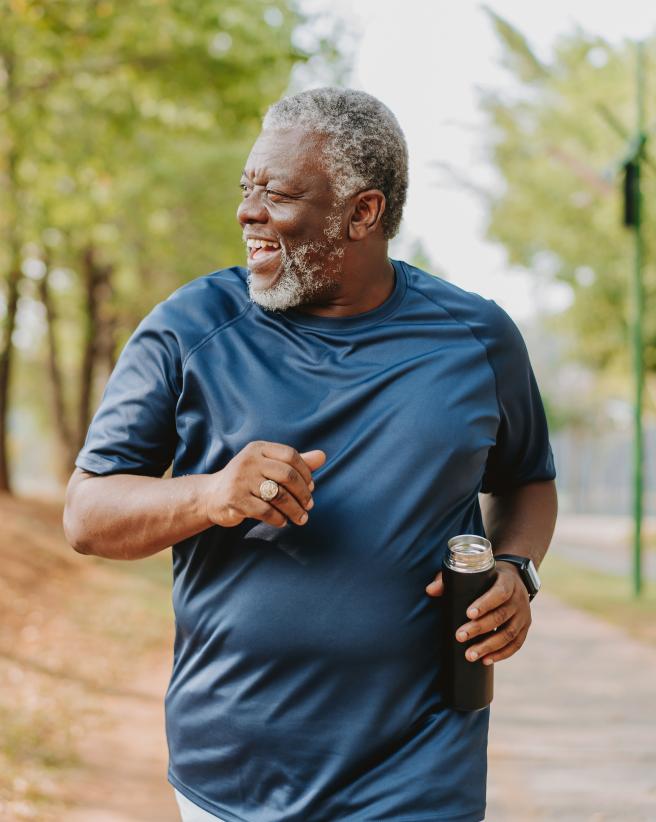 older gentleman walking on tree-lined trail