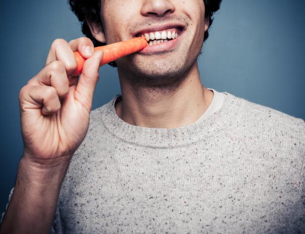Young man eating a carrot