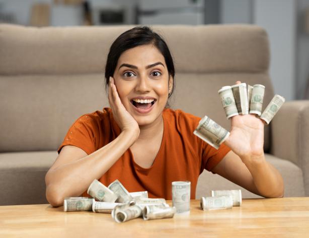 happy woman with US dollars wrapped around fingers