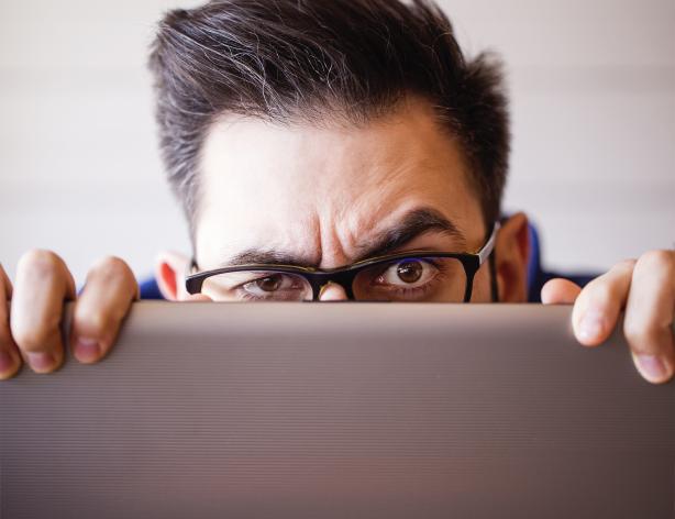 man peaking over his computer