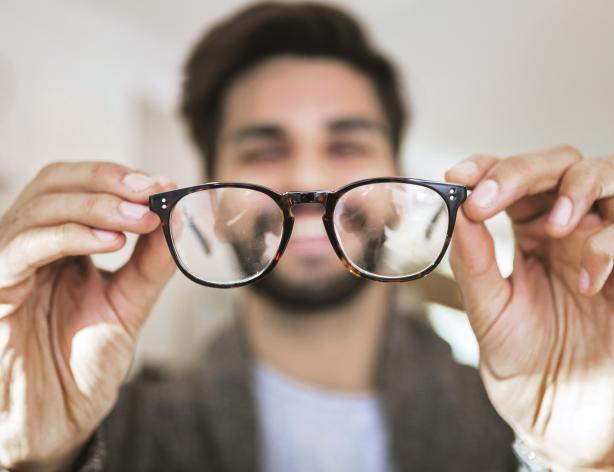 Man holding glasses away from his face