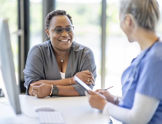 medical professional with paperwork looking at smiling woman