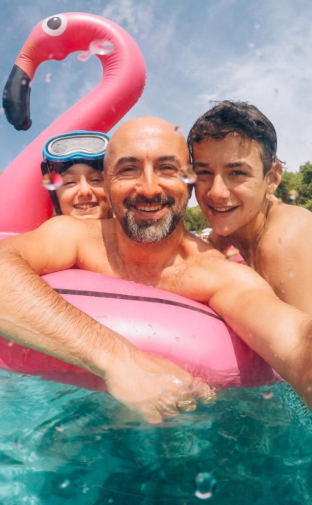 Man and two children in a pool on a flamingo floatie