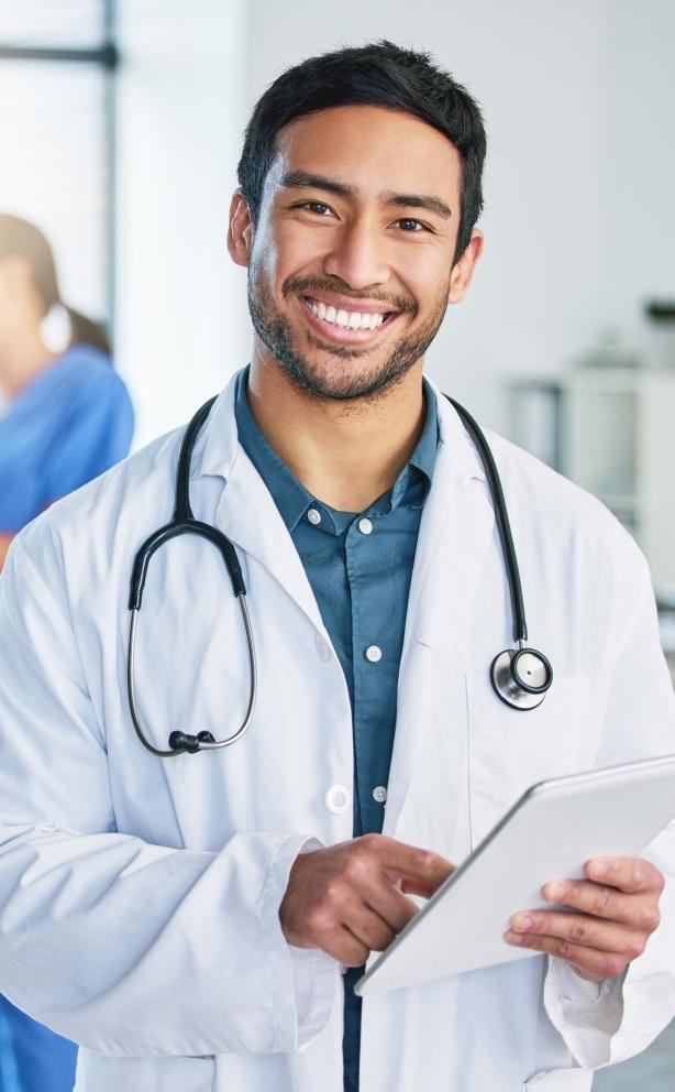 smiling doctor with stethoscope and clipboard in hospital setting