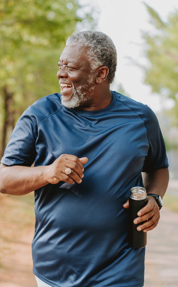 older gentleman walking on tree-lined trail