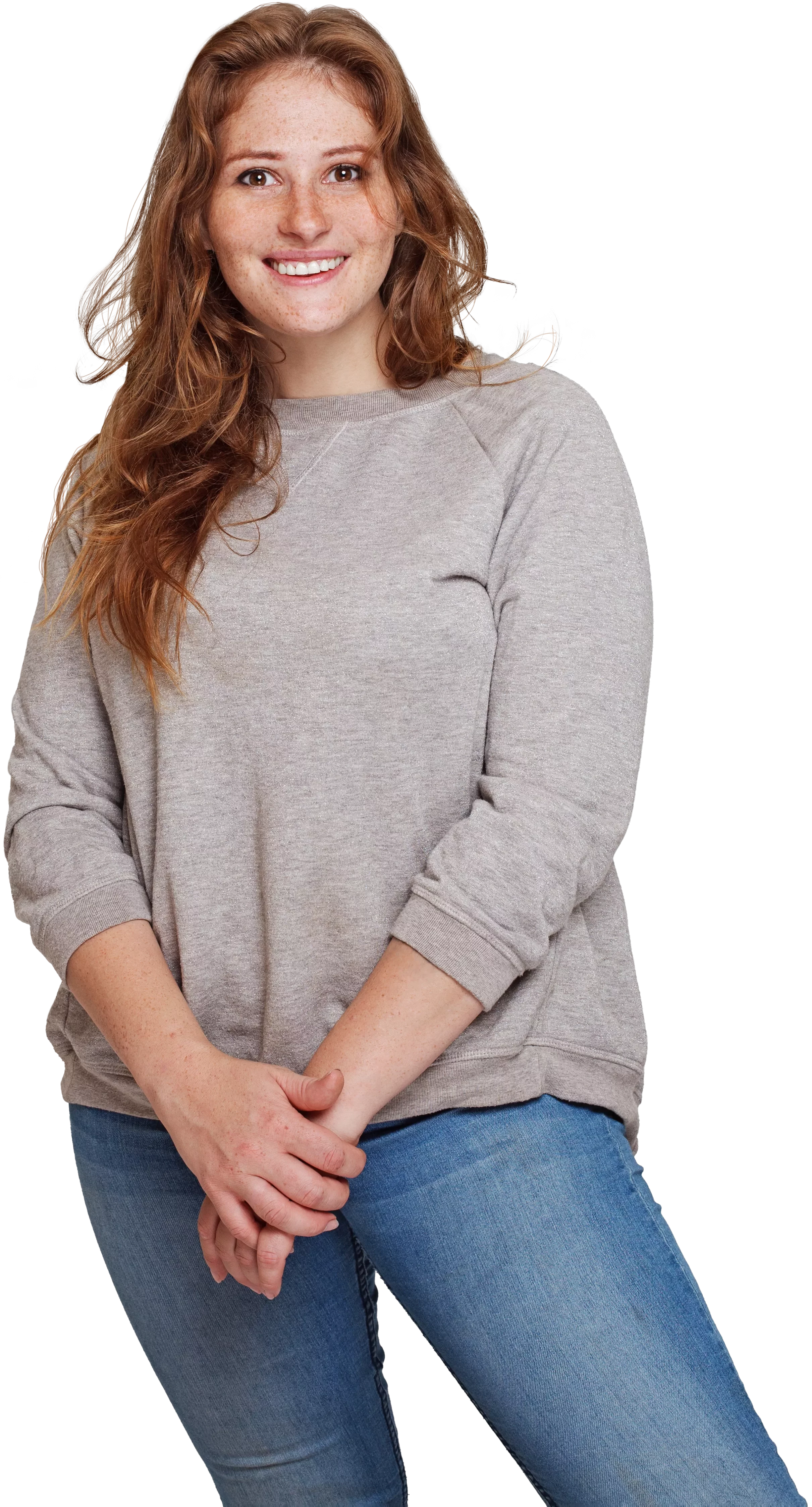 woman in sweatshirt and jeans smiling and standing with hands together